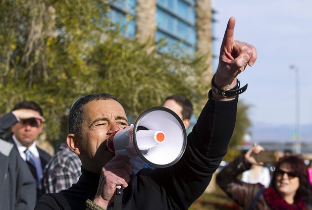 Richard Birt points to the sun as she speaks to solar supporters during a rally in front of Public Utilities Commission offices Wednesday, Jan 13, 2016. Birt said he has been off the grid for 10 years.