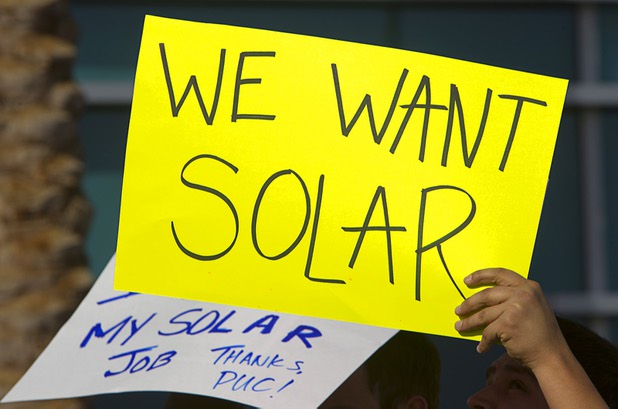 Solar supporters hold signs during a rally in front of Public Utilities Commission offices Wednesday, Jan 13, 2016.
