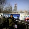 A man carries his luggage and a bag of fruits past billboards showing Chinese government propaganda "China Dream" and the scenic of Central Business District near a construction site in Beijing, Tuesday, Jan. 19, 2016. China's economic growth slowed to a six-year low in the latest quarter as trade and consumer spending weakened, deepening a downturn that has fueled anxiety abroad over its impact on an uncertain global outlook. 