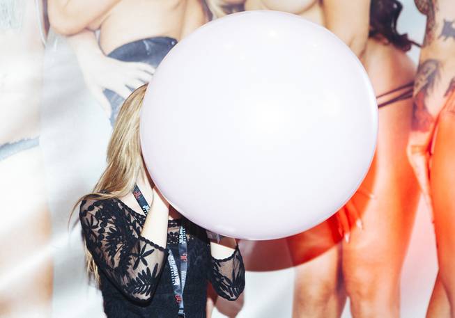 A model blows up a balloon at a booth during ...