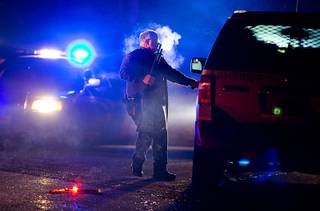 A Oregon State police officer stands by a vehicle as police officers block Highway 395 in Seneca, Ore., Tuesday, Jan. 26, 2016. Authorities said shots were fired Tuesday during the arrest of members of an armed group that has occupied a national wildlife refuge in Oregon for more than three weeks. (Dave Killen/The Oregonian via AP)