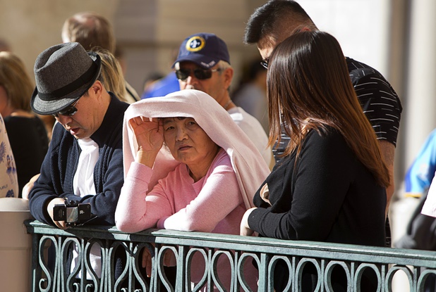 A woman shields herself from the sun as she waits for Chinese New Year celebrations at the Venetian and Palazzo Monday, Feb. 8, 2016. The Chinese New Year, the Year of the Monkey, began Monday.
