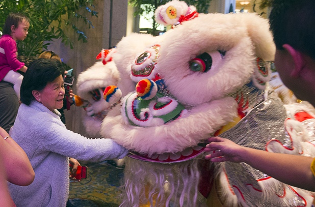 A woman "feeds" a lucky red envelope to a lion dancer during Chinese New Year celebrations at the Venetian and Palazzo Monday, Feb. 8, 2016. The Chinese New Year, the Year of the Monkey, began Monday.