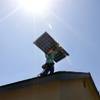 A SolarCity employee installs solar panels on a house June 27, 2014, in Camarillo, Calif. SolarCity, the nation’s largest provider of rooftop systems, is among a cluster of companies built with the aid of government subsidies and utility incentives now facing deep uncertainties and accelerating losses despite unflagging consumer interest and surging growth in renewable energy. 