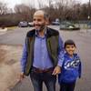 In this Friday, Dec. 18, 2015, photo Syrian refugee Ahmad Alkhalaf, 9, and his father Dirgam Alkhalaf stand outside Ahmad's school in Sharon, Mass. Ahmad who arrived in the Boston area this past summer for medical treatment, said he used to have restless nights when he would relive his mother’s screams from the night a bomb killed three of his siblings and left him without arms. But those sounds, he said, have largely faded.
