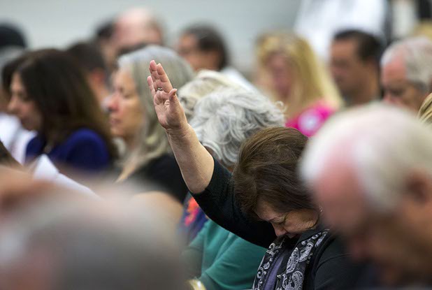 People bow their heads in prayer at the start of a campaign stop by Republican presidential candidate Ben Carson at the Mountain Shadows Community Center in Summerlin Tuesday, Feb. 23, 2016.