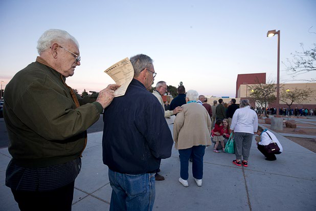 Raymond Puckett, left, fills out a national poll questionnaire on the back of his son Dennis as they wait in line at the Western High School GOP caucus site Tuesday, Feb. 23, 2016.