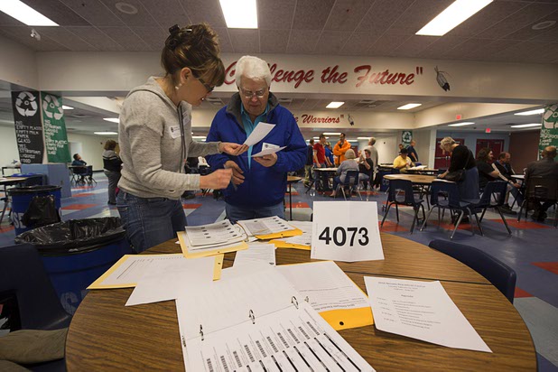 Volunteer Theresa Hargrove hands a ballot to Ken Scherer on Tuesday, Feb. 23, 2016, at the Western High School GOP caucus site.