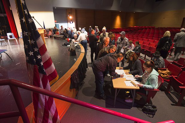 Caucus-goers check in with their precinct tables at the Western High School GOP caucus site Tuesday, Feb. 23, 2016.