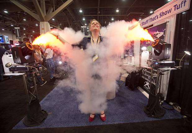 Lily Phillips-Leavitt poses between two Maniac LED moving head fog machines during the 2016 Nightclub & Bar convention at the Las Vegas Convention Center Tuesday, March 8, 2016.