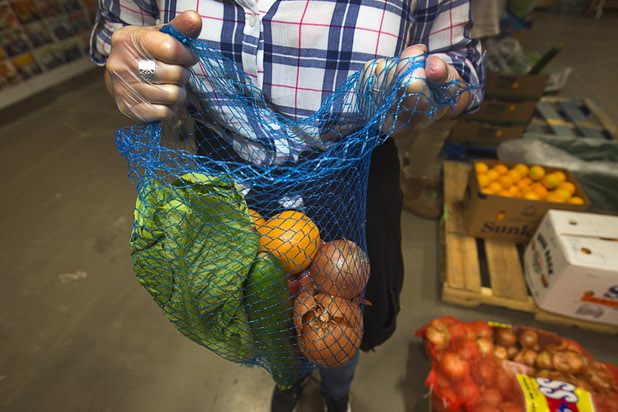 A volunteer holds a bag of produce for the Senior Share program at Three Squares north campus, 4220 N. Pecos Rd., Wednesday, March 16, 2016.