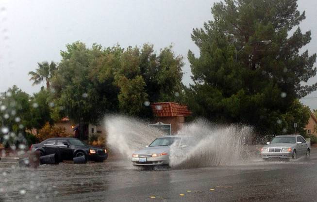A car splashes through water flowing across Eastern Avenue near Mohigan Way on Saturday, April 9, 2016, after a thunderstorm dumped heavy rain on the Las Vegas Valley. A flash flood was issued for area after the storm.