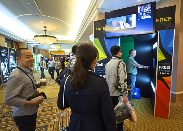 People line up for a SelfieW.me photo booth during CinemaCon at Caesars Palace Tuesday, April 12, 2016. The booth puts your photo into a movie scene. CinemaCon is a convention for movie theater owners.