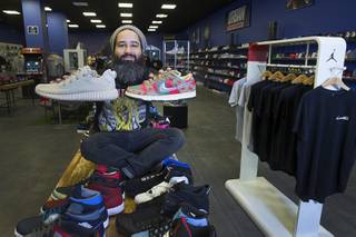 Owner Jaysse Lopez poses with some rare and pricey sneakers at Urban Necessities in the Boulevard mall Sunday, April 17, 2016. The Yeezy Oxford sneaker, left, is designed by Kanye West. At right is a rare Nike 