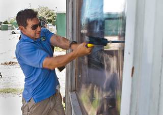 Anthony Krieg with the City of Las Vegas Code Enforcement takes a swing at a SecureView window product being demonstrated by Safeguard Properties to Las Vegas police and fire fighters at a former squatter house along Shiloah Drive on Thursday, May 5, 2016.