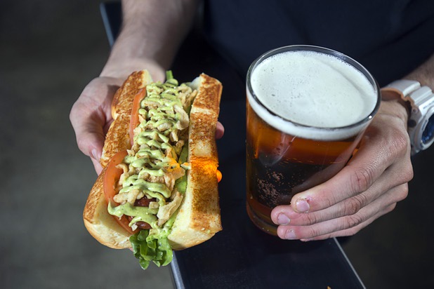 Adam Roll, general manager of Dog Haus, holds with a "Sooo Cali" (wild arugula, spicy basil aioli, crispy onions, avocado, tomato on a grilled Hawaiian roll) dog and a beer at the restaurant at 4480 S Paradise Rd. Monday, May 9, 2016. The California-based chain specializes in creative hot dogs, burgers, sausages & fries. The Las Vegas restaurant opened in March.