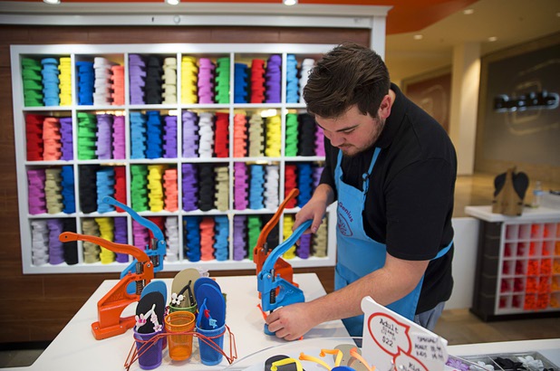 "Flip-flop genius" Christian Muniz assembles a customized flip flop at the Fashion Show mall kiosk location Monday, May 23, 2016. The company allows you to decorate your flip-flops, then watch a flip-flop genius put it together in front of you.