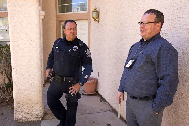 North Las Vegas Police Officer Scott Vaughn left, and code enforcement officer Matthew Meanea talk in front of a home that had been occupied by squatters in North Las Vegas Wednesday, May 18, 2016.