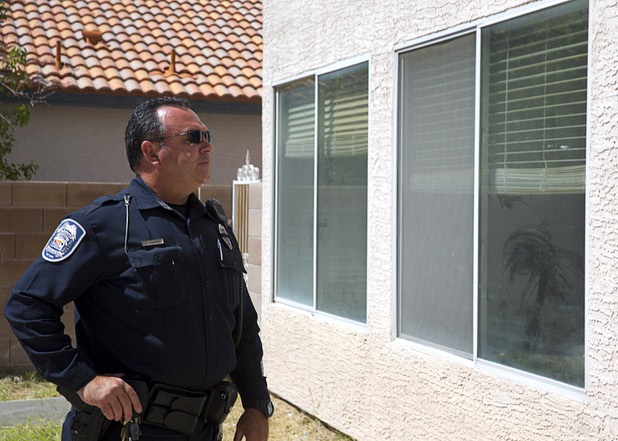 North Las Vegas Police Officer Scott Vaughn looks over a home that had been occupied by squatters in North Las Vegas Wednesday, May 18, 2016.