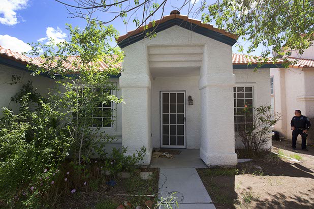 North Las Vegas Police officer Scott Vaughn stands by a vacant home that had been occupied by squatters in North Las Vegas Wednesday, May 18, 2016.