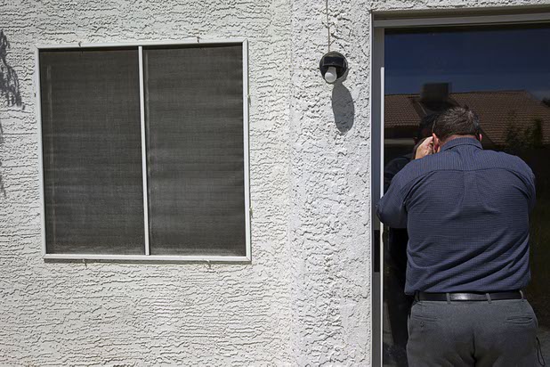 North Las Vegas code enforcement officer Matthew Meanea looks into a vacant home that had been occupied by squatters in North Las Vegas Wednesday, May 18, 2016.