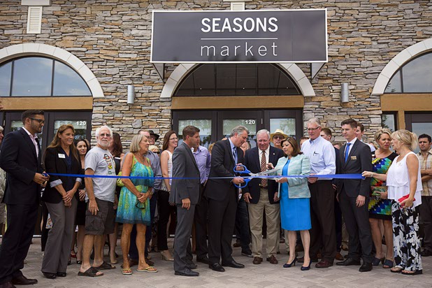 Patrick Parker (with scissors), president of Raintree Investments, prepares to cut a ceremonial ribbon with residents, dignitaries and other executives during the official opening of the Seasons Market at Lake Las Vegas in Henderson Tuesday, June 21, 2016. The neighborhood grocery store and specialty market is located in MonteLago Village.