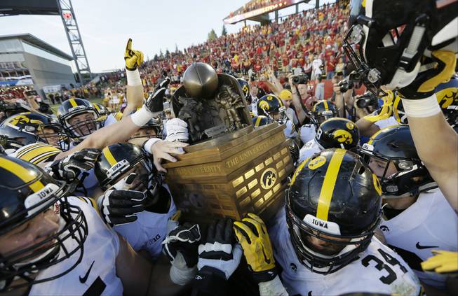 Iowa players carry the Cy-Hawk trophy off the field after their 31-17 victory over Iowa State in an NCAA college football game, Saturday, Sept. 12, 2015, in Ames, Iowa. 