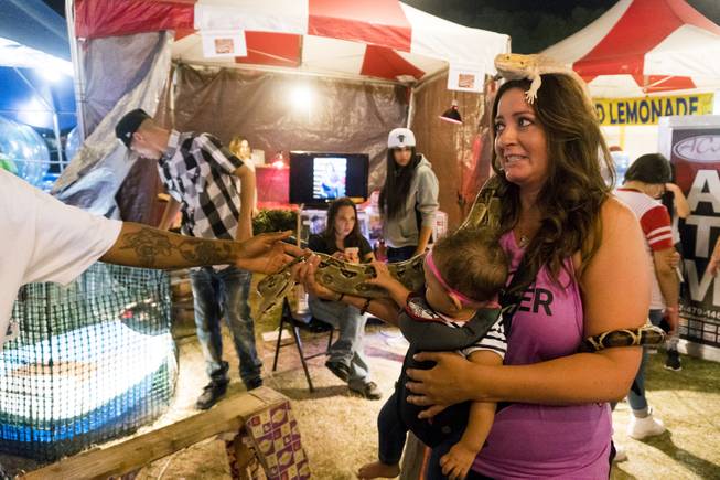 A festival goer poses with reptiles and her baby for a photo during the 37th Annual San Gennaro Feast Festival at Craig Ranch Park in North Las Vegas, Friday, Sept. 16, 2016.