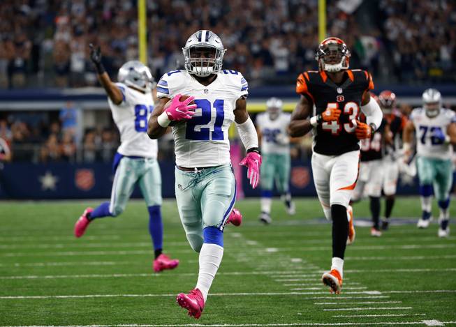 Dallas Cowboys running back Ezekiel Elliott, center, approaches the end zone after a long run for a touchdown as Cincinnati Bengals free safety George Iloka, right, gives chase in the second half of an NFL game Sunday, Oct. 9, 2016, in Arlington, Texas.