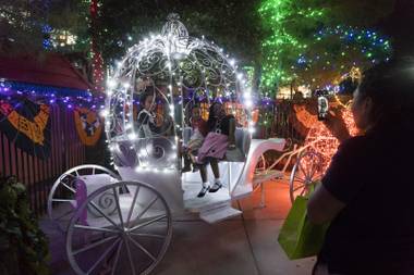 Visitors take pictures at the lit up pumpkin carriage during the opening night of the 4th annual HallOVeen at Opportunity Village’s Magical Forest, Friday, Oct. 14, 2016.
