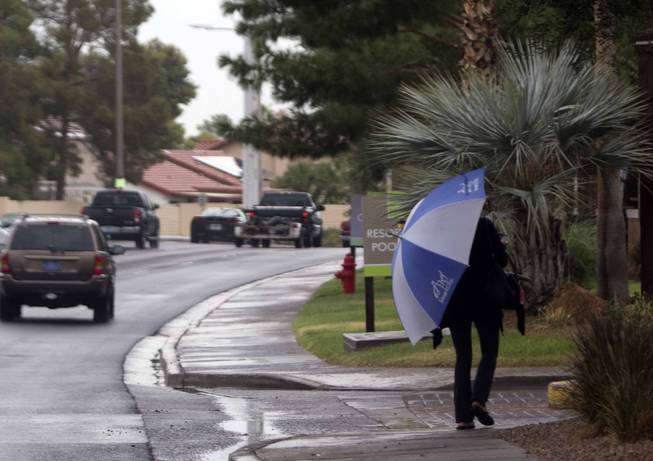 A woman with an umbrella walks in light rain along Green Valley Parkway in Henderson Monday, Oct. 24, 2016. 