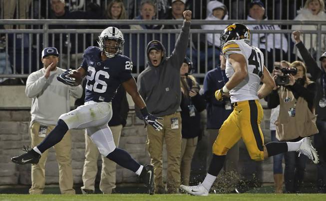 Penn State's Saquon Barkley (26) runs in for a touchdown as Iowa's Bo Bower (41) chases after him during the second half of an NCAA college football game in State College, Pa., Saturday, Nov. 5, 2016. Penn State won the game 41-14. 