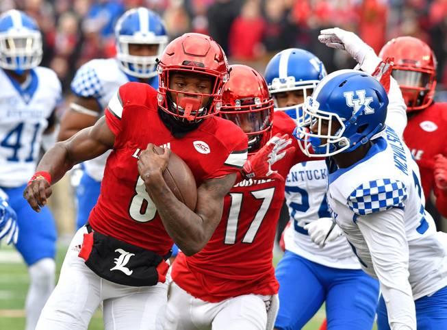 Louisville quarterback Lamar Jackson, left, attempts to avoid Kentucky's Marcus McWilson, right, during the first half of an NCAA college football game Saturday, Nov. 26, 2016, in Louisville, Ky.