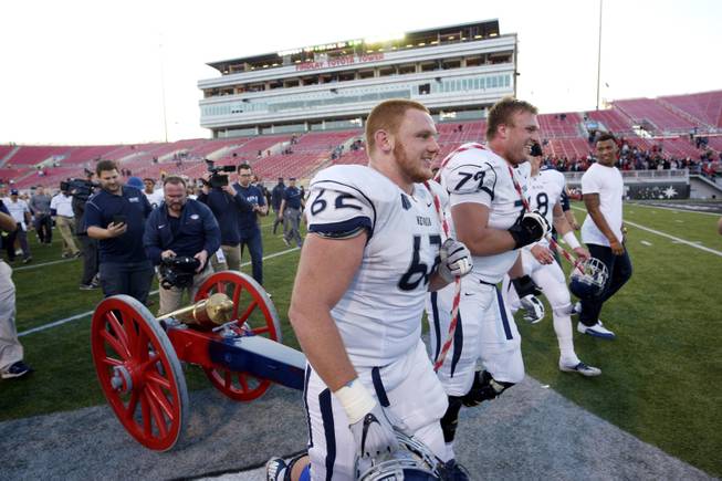 UNR offensive linemen Nathan Goltry, left, and Jacob Henry drag the Fremont Cannon back to their locker room after their 45-10 win against UNLV Saturday, Nov. 26, 2016, at Sam Boyd Stadium.