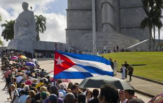 People wait in line to pay their final respects to the late Fidel Castro, at Revolution Plaza, the site of two days of tributes to the legendary leader, in Havana, Cuba, Monday, Nov. 28, 2016. Thousands of Cubans began lining up early carrying portraits of Castro, flowers and Cuban flags for the start of week-long services bidding farewell to the man who ruled the country for nearly half a century. 