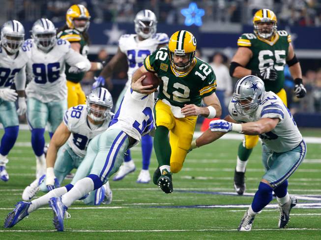 Green Bay Packers quarterback Aaron Rodgers (12) rushes for a gain as the Dallas Cowboys' Sean Lee (50) and Anthony Brown (30) defend during the second half of an NFL divisional playoff game Sunday, Jan. 15, 2017, in Arlington, Texas.