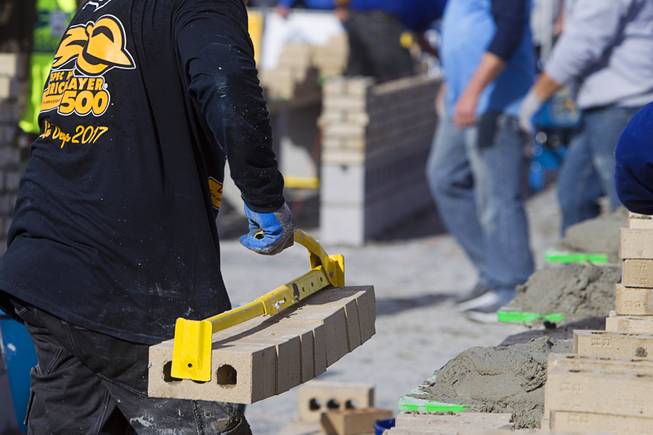 A tender carries bricks to his mason in the 15th Anniversary Spec Mix Bricklayer 500 during the World of Concrete convention at the Las Vegas Convention Center Wednesday, Jan. 18, 2017. Top masons from across North America, and one from England, competed to build the best brick wall in one hour.