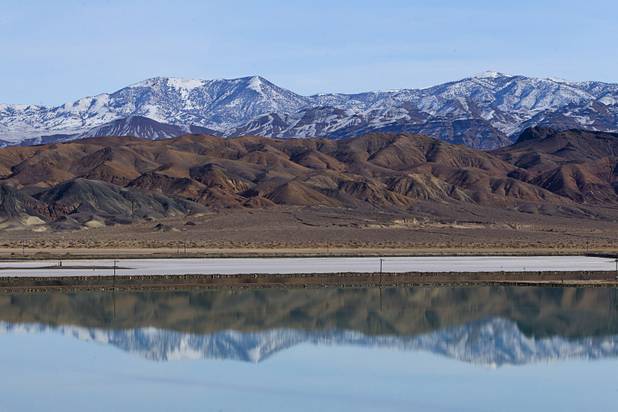 Mountains are reflected in an evaporation pond at the Silver Peak lithium mine near Tonopah, Nev. Monday, Jan. 30, 2017.