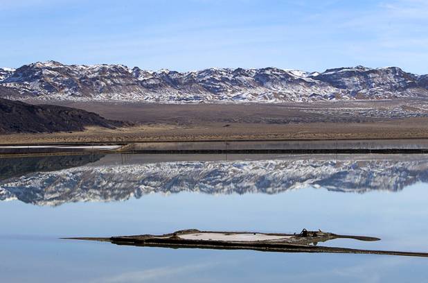 Mountains are reflected in an evaporation pond at the Silver Peak lithium mine near Tonopah, Nev. Monday, Jan. 30, 2017.
