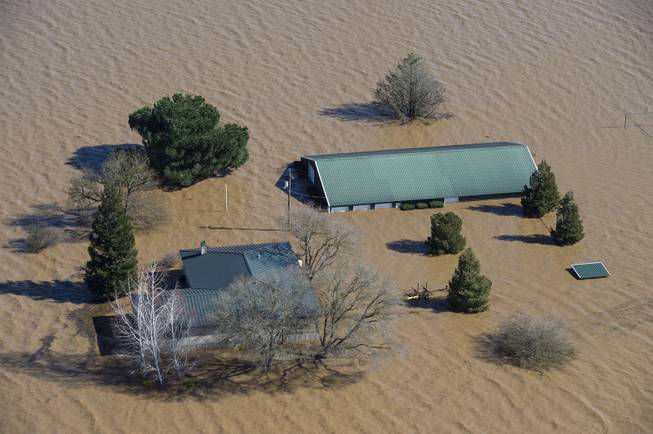Water from the Cosumnes and Mokelumne rivers floods a house and barn north of Twin Cities Road east of Interstate 5, Saturday, Feb. 11, 2017 in Elk Grove, Calif. Water started flowing over an emergency spillway at the nation's tallest dam, on Lake Oroville, for the first time Saturday after erosion damaged the Northern California dam's main spillway. (Randy Pench/The Sacramento Bee via AP)