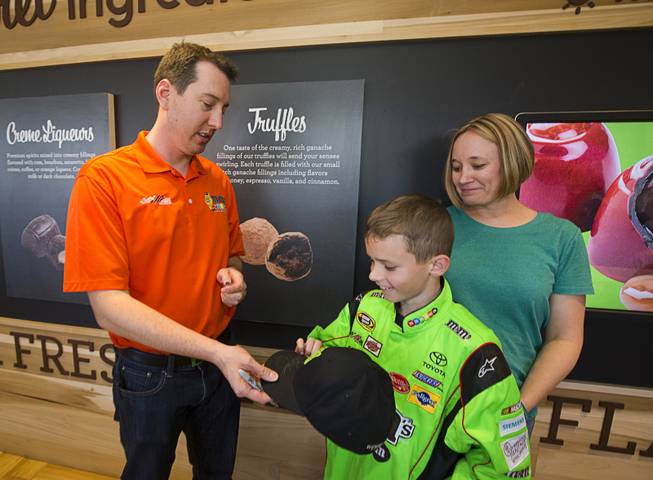 NASCAR driver Kyle Busch signs a cap for Austin Boring, 10, during an appearance at the Ethel M Chocolates factory in Henderson Thursday, March 9, 2017. Austin's moth Christy looks on at right.