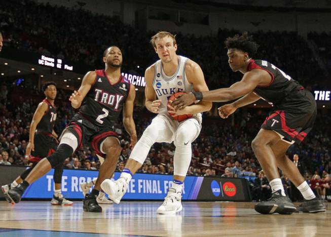 Duke's Luke Kennard, center, is fouled as he drives between Troy's Jordon Varnado, right, and Jeremy Hollimon, left, during the second half in a first-round game of the NCAA men's college basketball tournament in Greenville, S.C., Friday, March 17, 2017. 
