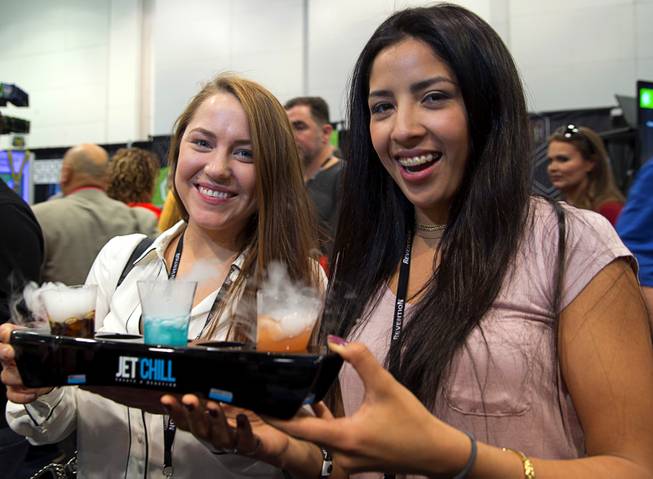 Corinne Grove, left, and Johana Herrera Amaya of Crab Island Cantina in Destin, Fla., try "smoking" drinks at the JetChill booth during the Nightclub & Bar Convention and Trade Show at the Las Vegas Convention Center Tuesday, March 28, 2017. The automated system contains dry ice powder in the base of the glass that lets the vapor rise up but keeps the dry ice powder in the base.