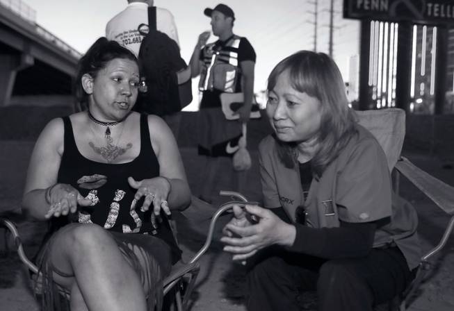 Pharmacist Khanh Pham (right) chats with a woman as her group moves through a homeless camp offering help.