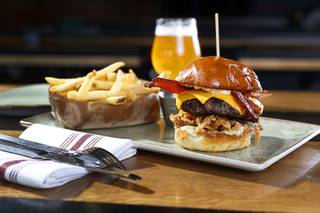 The White Truffle Bacon Aioli Burger at Public School 702 in Downtown Summerlin Monday, April 17, 2017. The bacon and cheese burger with a white truffle and cherry vinaigrette aioli is served on crispy onion straws. Paired with your choice of three beers, the burger and fries combo is $13.00 through April.