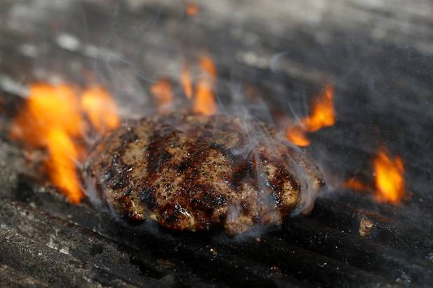The White Truffle Bacon Aioli Burger cooks on the grill at Public School 702 in Downtown Summerlin Monday, April 17, 2017. The bacon and cheese burger with a white truffle and cherry vinaigrette aioli is served on crispy onion straws. Paired with your choice of three beers, the burger and fries combo is $13.00 through April.