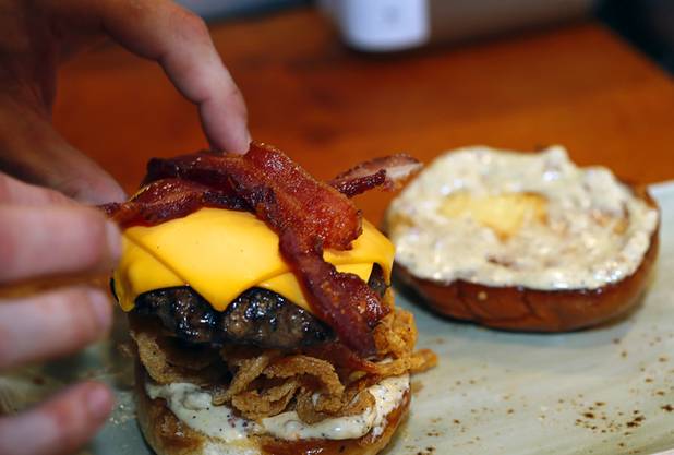 Chef Jeremy Chandler creates a White Truffle Bacon Aioli Burger at Public School 702 in Downtown Summerlin Monday, April 17, 2017. The bacon and cheese burger with a white truffle and cherry vinaigrette aioli is served on crispy onion straws. Paired with your choice of three beers, the burger and fries combo is $13.00 through April.