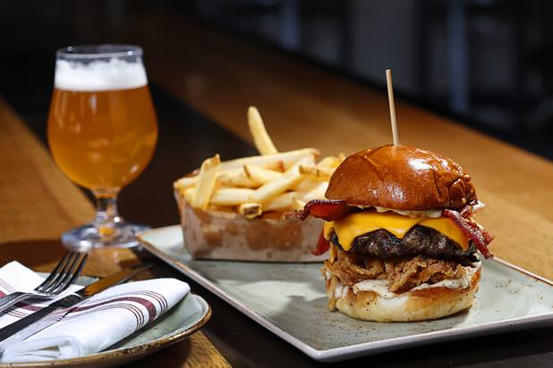The White Truffle Bacon Aioli Burger at Public School 702 in Downtown Summerlin Monday, April 17, 2017. The bacon and cheese burger with a white truffle and cherry vinaigrette aioli is served on crispy onion straws. Paired with your choice of three beers, the burger and fries combo is $13.00 through April.