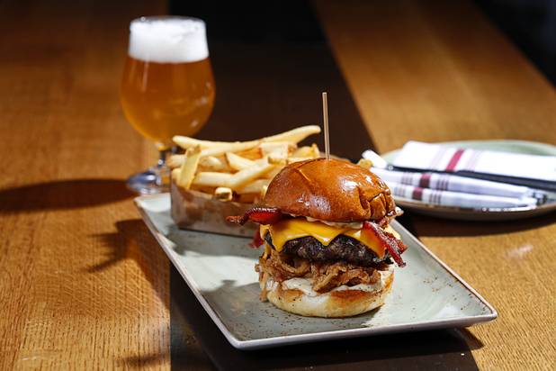 The White Truffle Bacon Aioli Burger at Public School 702 in Downtown Summerlin Monday, April 17, 2017. The bacon and cheese burger with a white truffle and cherry vinaigrette aioli is served on crispy onion straws. Paired with your choice of three beers, the burger and fries combo is $13.00 through April.
