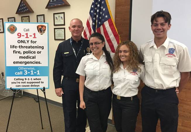 Clark County Fire Chief Greg Cassell stands with Veterans Tribute Career and Technical Academy seniors Laura Lomeli, Samantha Garavi and Ivan Farias, who won the department’s second annual PSA contest on when to call 911. The three are pictured Monday, April 17, 2017, at a news conference at the school.